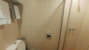 A small bathroom with a toilet, a shower stall, and a towel rack with towels.