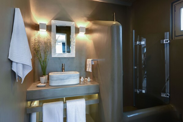 A modern bathroom with a large mirror, a round sink, and a shower area.