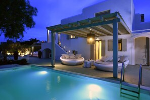 A modern pool area with a covered seating area and a staircase leading to an upper level.