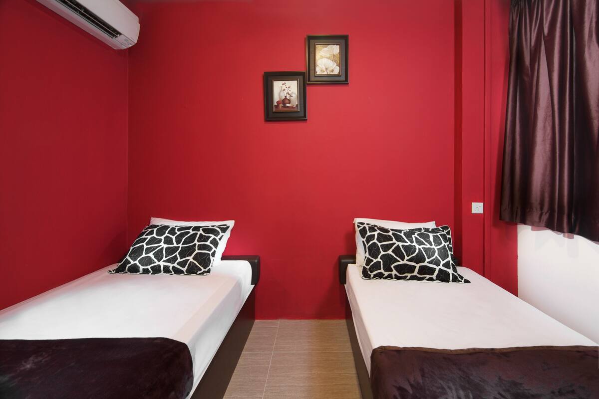 A room with two beds, red walls, and a small window.