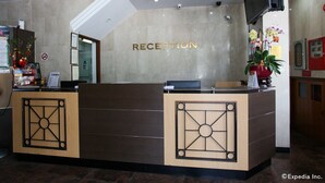 A reception desk with a 'RECEPTION' sign, a flat-screen TV, and a potted plant. - Tai Hoe Hotel (Singapore)