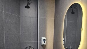 A modern bathroom with a toilet, a sink, a shower, and a hand dryer. - Tai Hoe Hotel (Singapore)