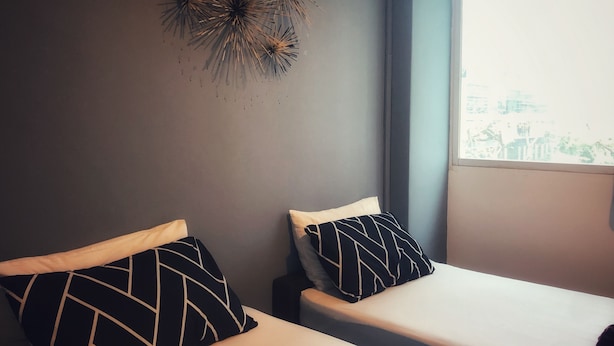 A bedroom with two beds, a window with a view, and a decorative wall piece. - Tai Hoe Hotel (Singapore)
