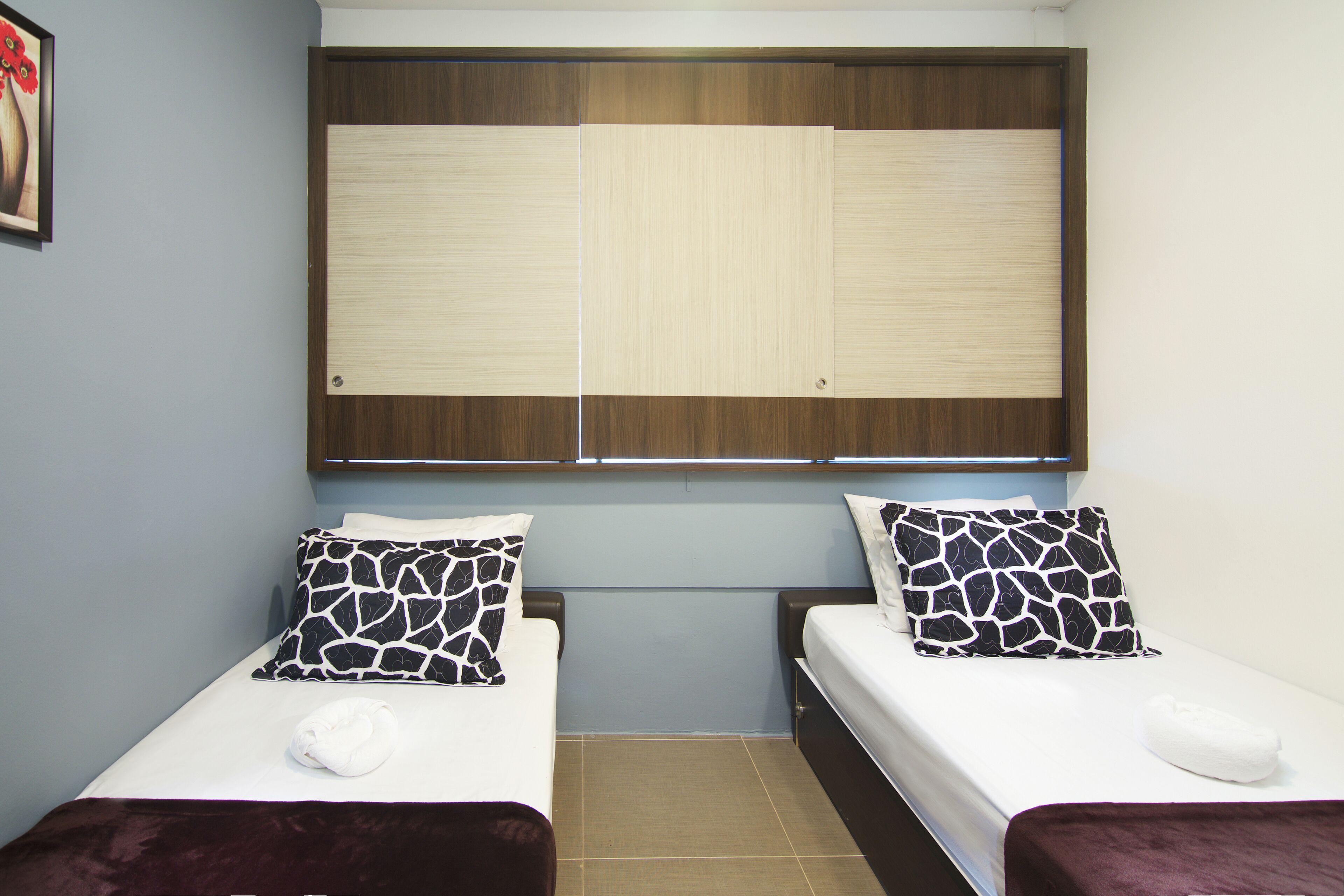 A room with two beds, each with a patterned pillow and a white towel.