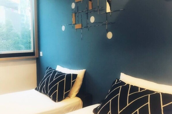 A bedroom with a bed, two pillows, a window, and a wall-mounted light fixture.