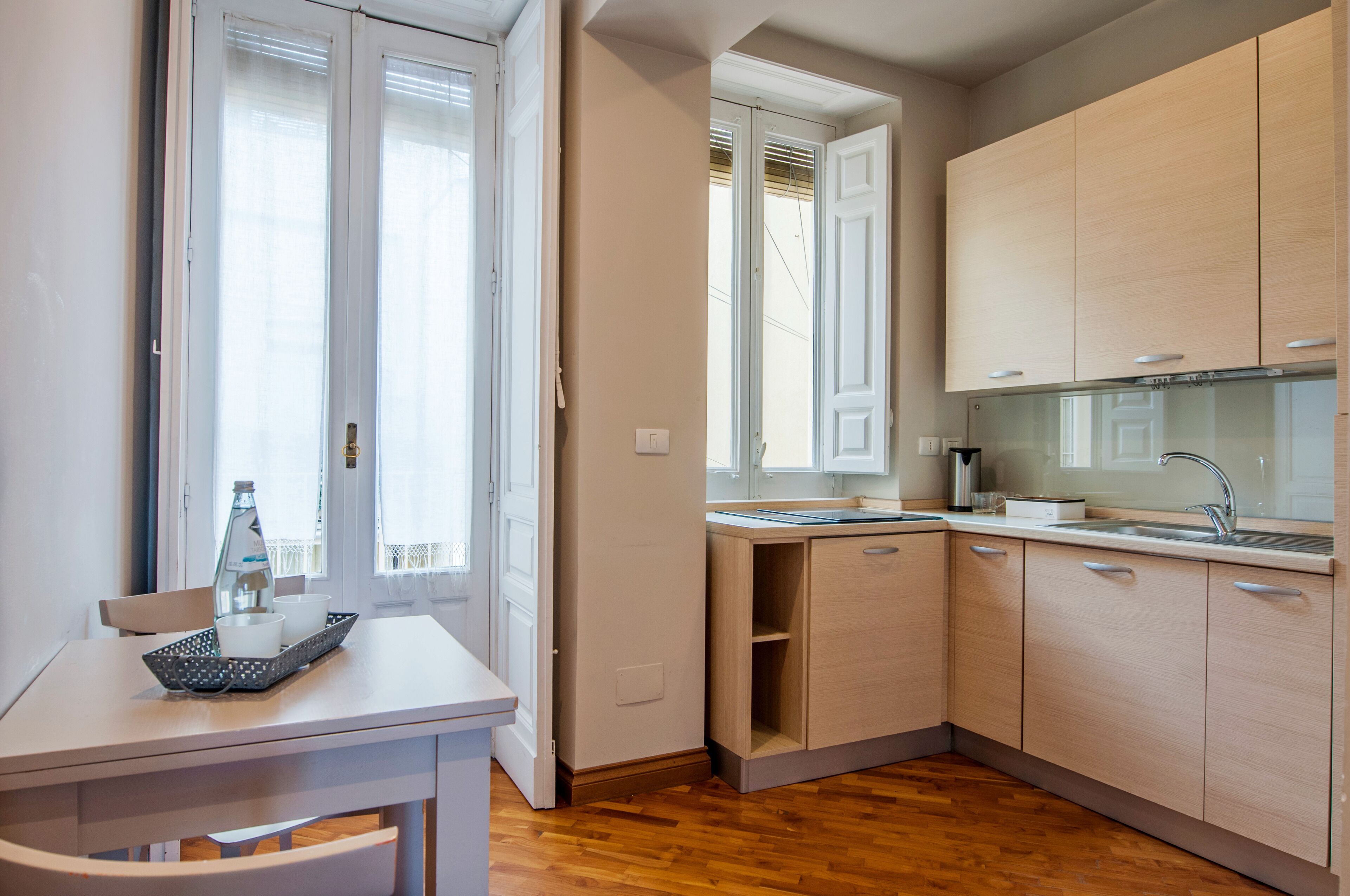 A compact kitchen with wooden cabinets, a sink, and a window with blinds.