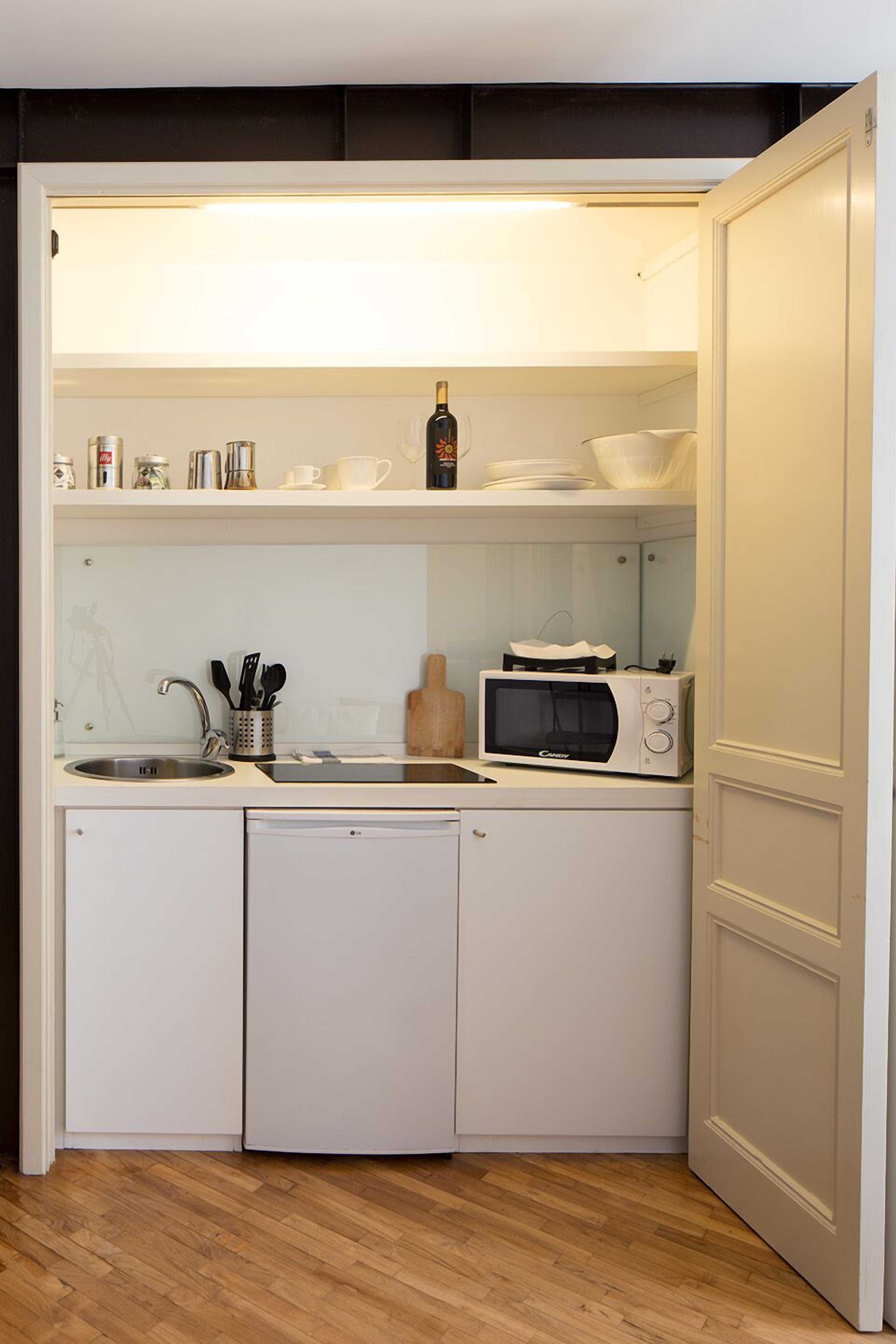 A compact kitchenette with a microwave, sink, and dishwasher.