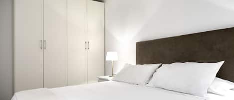 Une chambre d’hôtel moderne avec un grand lit, une table de chevet, une lampe et une armoire.