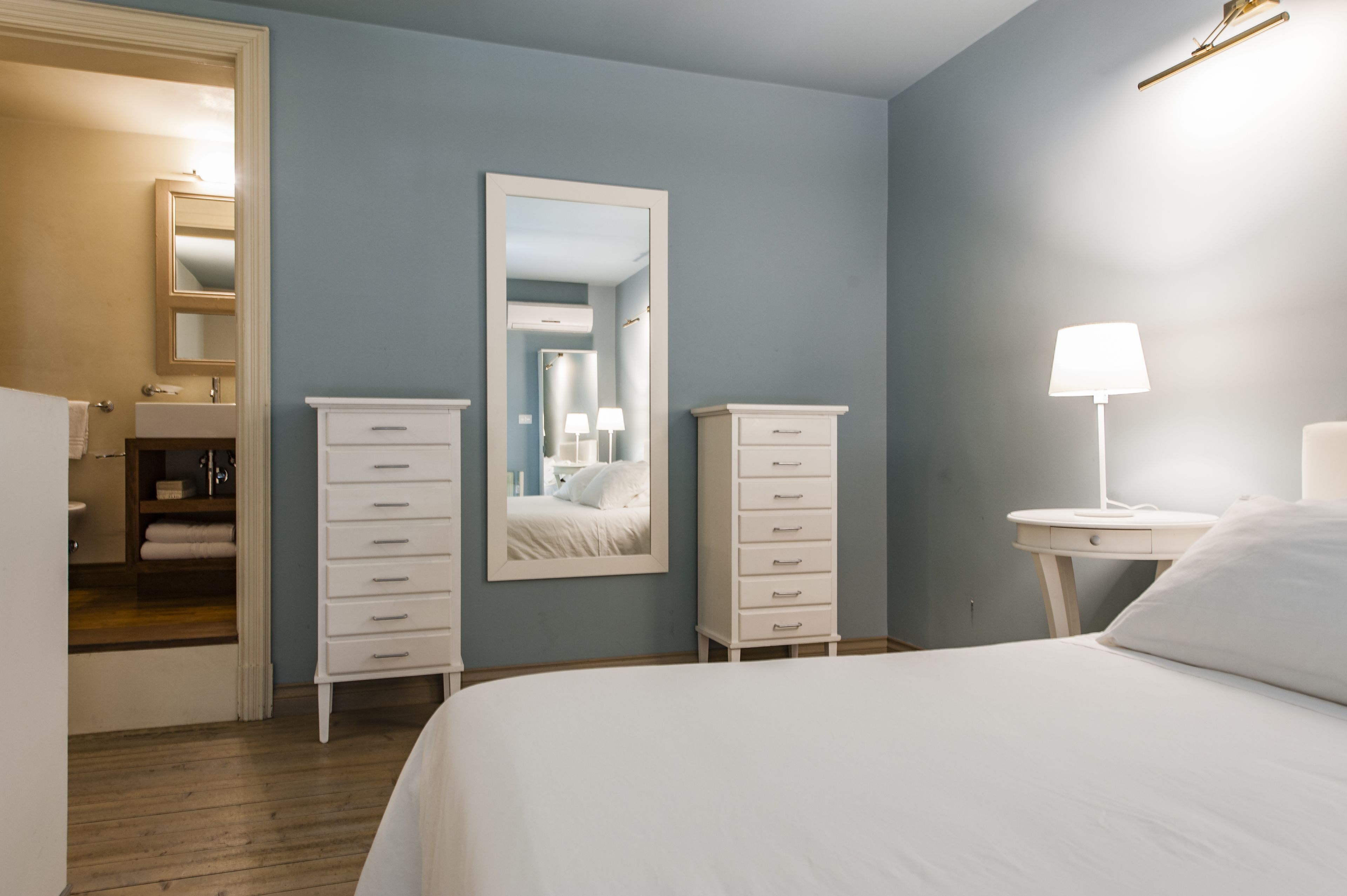 A bedroom with a bed, two nightstands, a dresser, a mirror, and a walk-in closet.