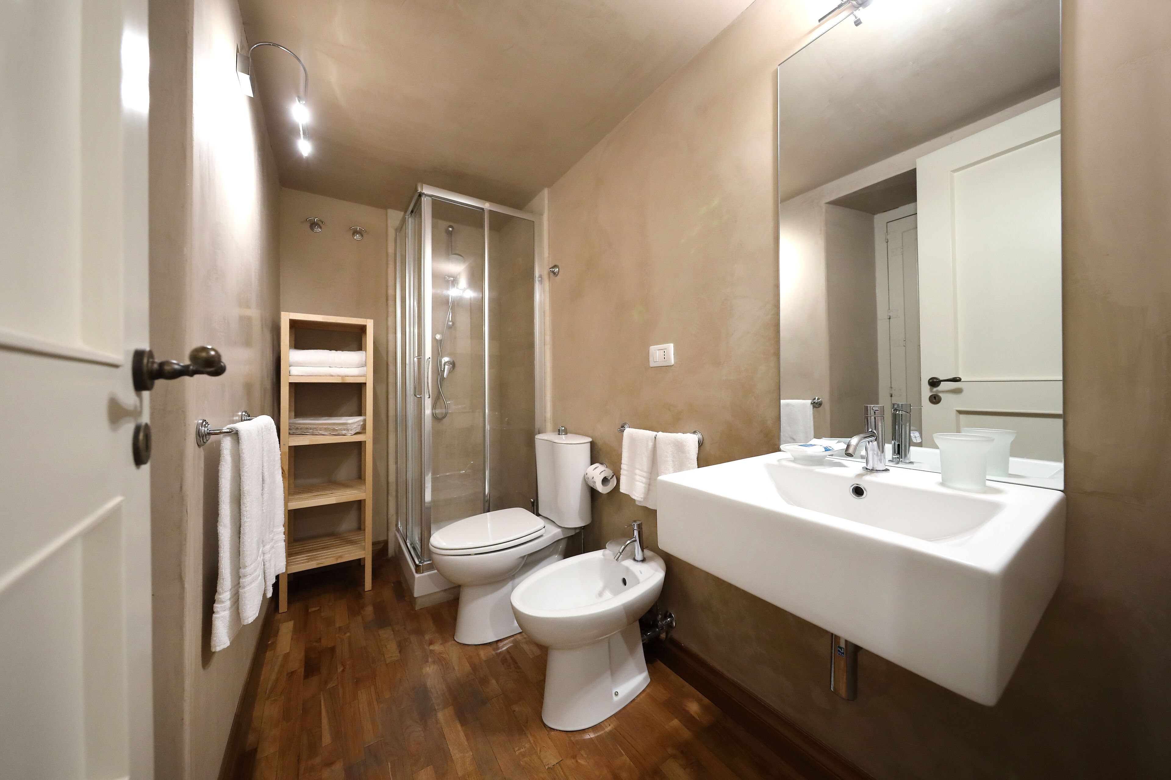 A bathroom with a shower, toilet, bidet, and a large sink.