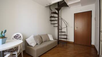 Una sala de estar moderna con una escalera espiral, un sofá, una mesa de comedor y piso de madera.