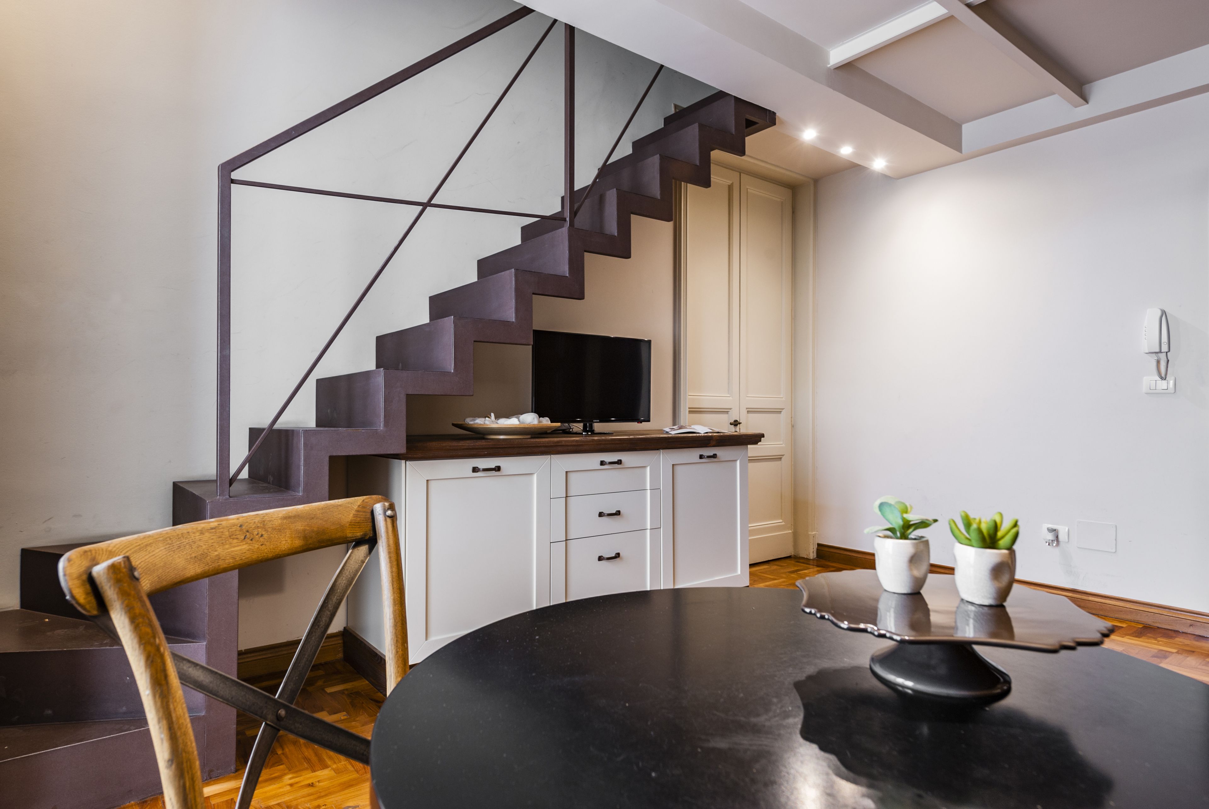 A modern kitchen with a black countertop, white cabinets, and a wooden chair.