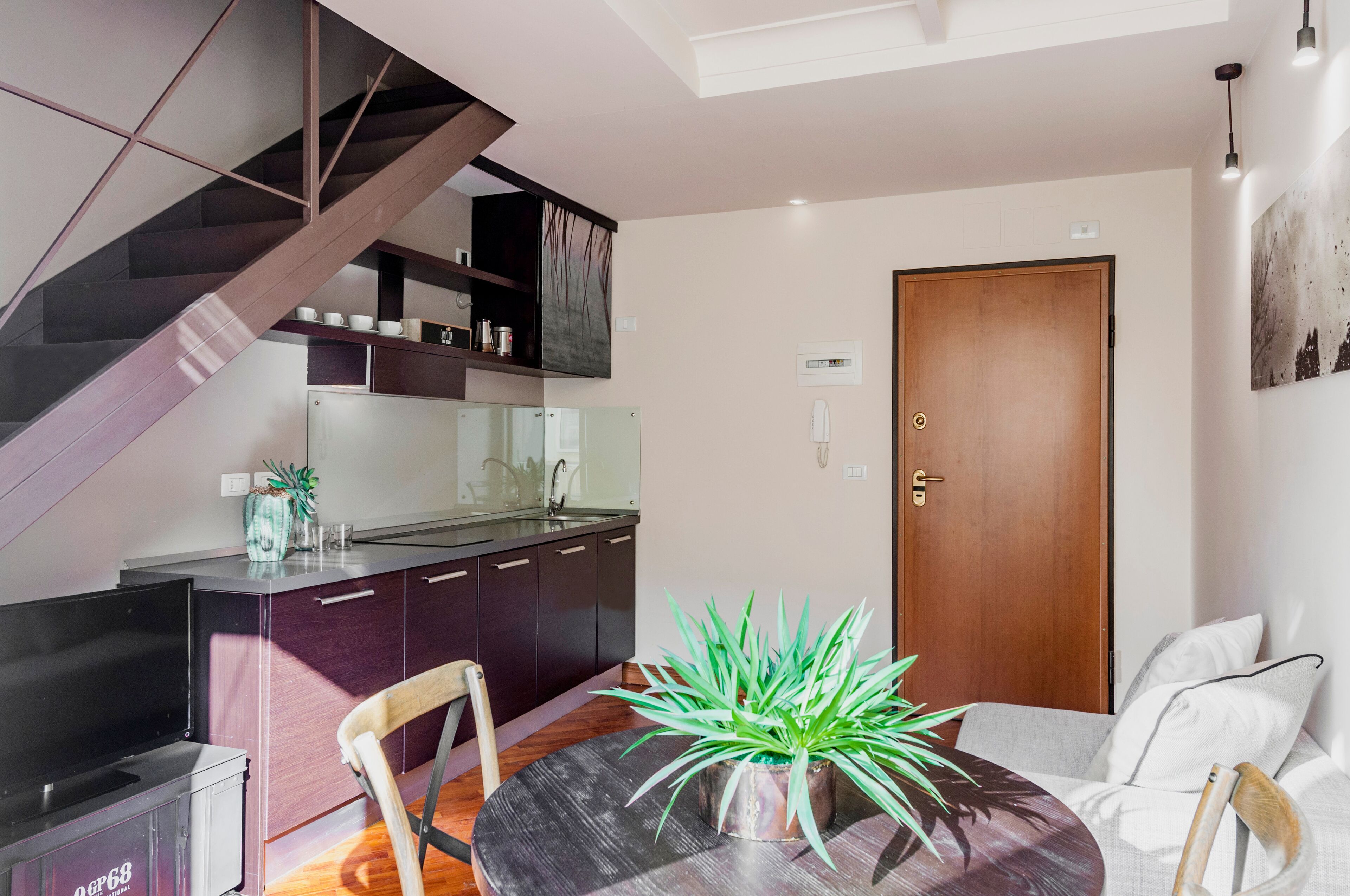 A modern kitchen with dark cabinetry, a built-in oven, and a dining area with a round table and chairs.
