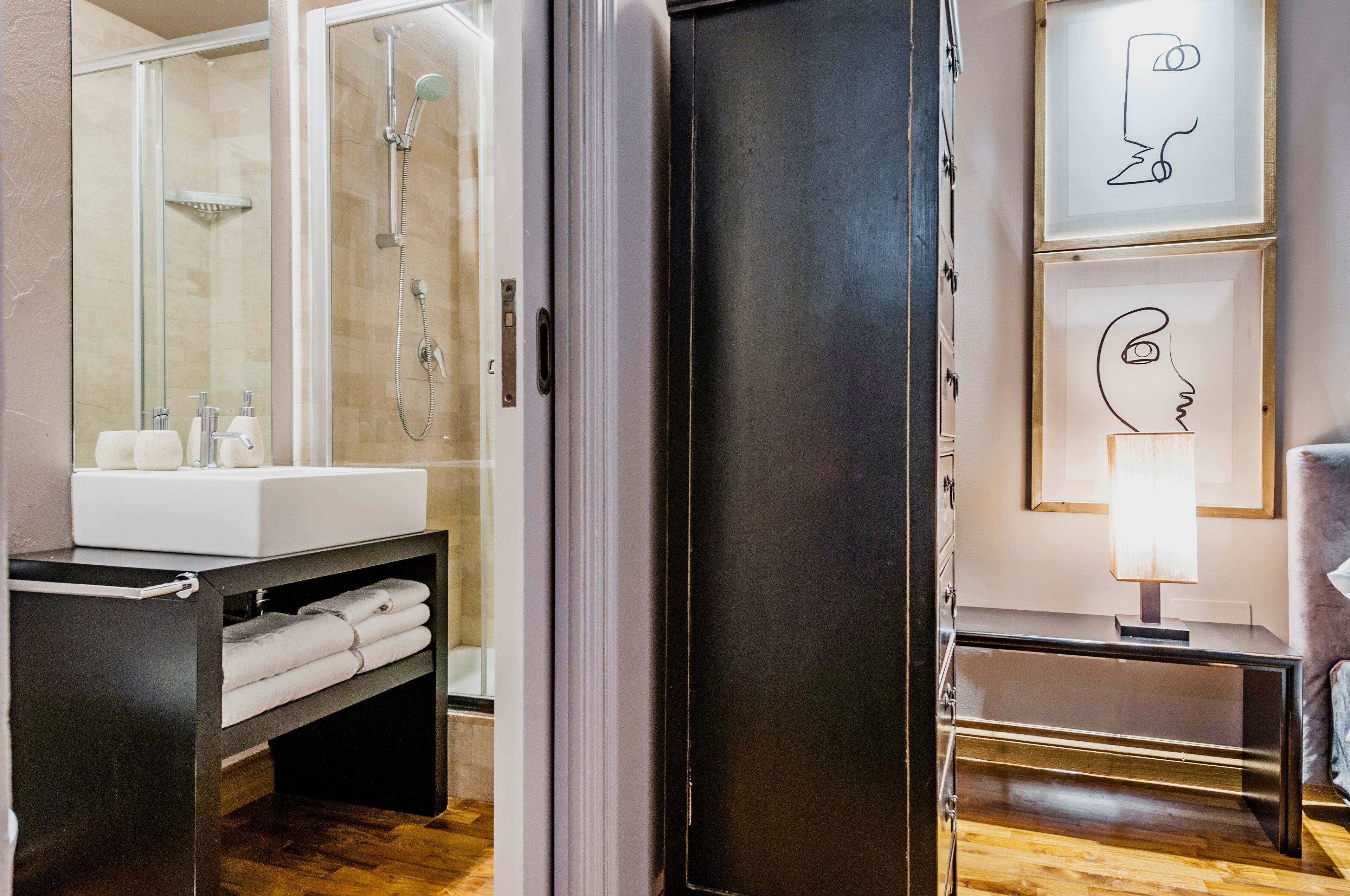 Un bagno moderno con doccia vetro, lavandino bianco e porta asciugamani.