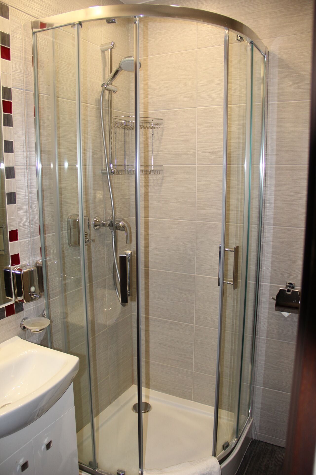 A glass-enclosed shower with a white sink and a towel rack.