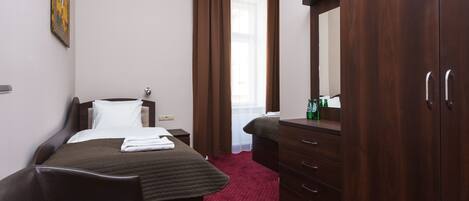 A hotel room with a bed, a dresser, a mirror, a ceiling fan, and a window with curtains.