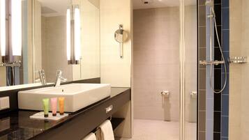 A modern bathroom with a large mirror, a sink, and a shower area.