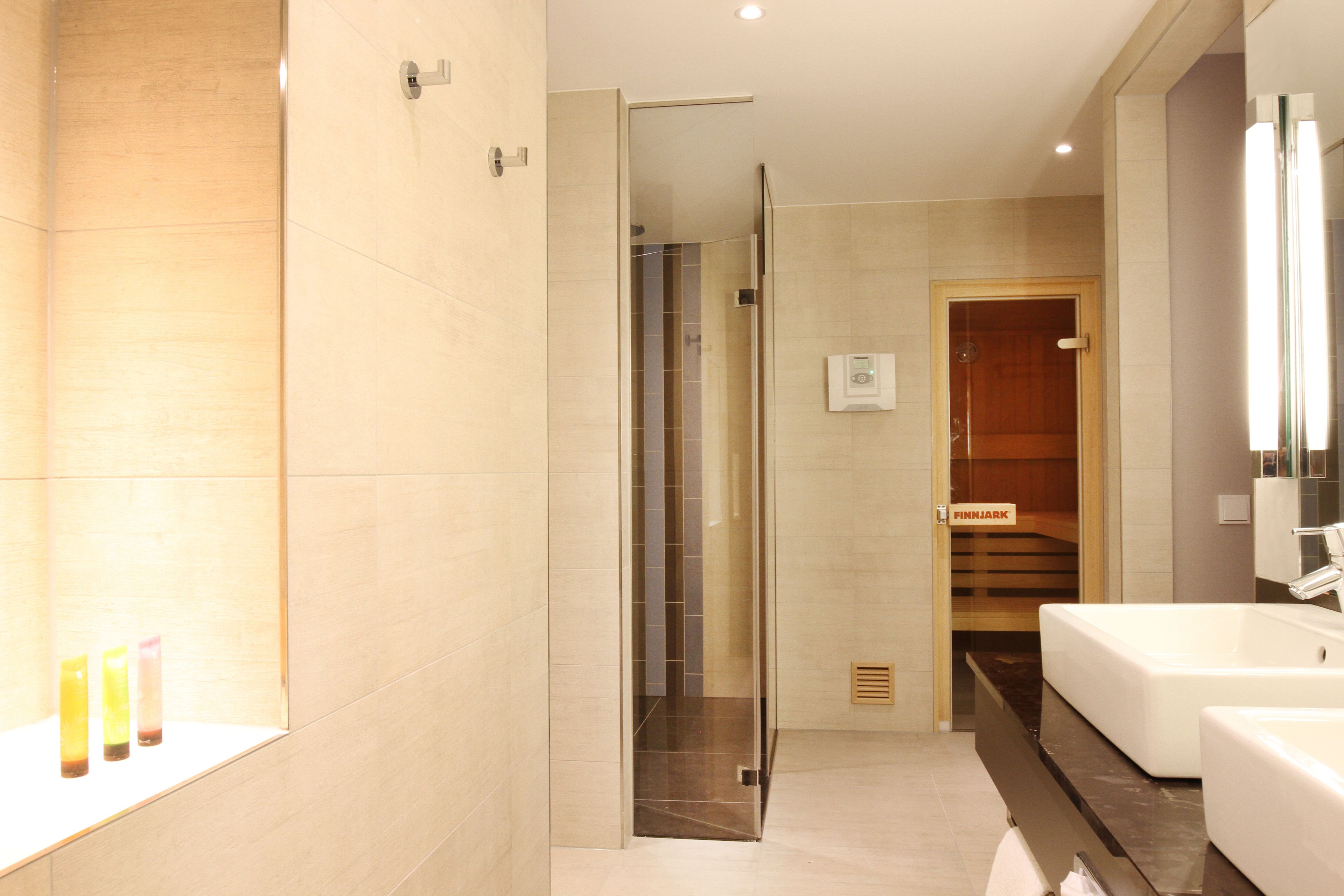 Ein modernes Badezimmer mit Duschkabine aus Glas, einer Holztür mit der Aufschrift 'FINNJARK' und einer großen, weißen Badewanne.