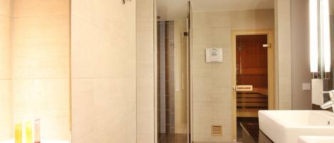 A modern bathroom with a glass shower enclosure, a wooden door labeled "FINNJARK," and a large white bathtub.