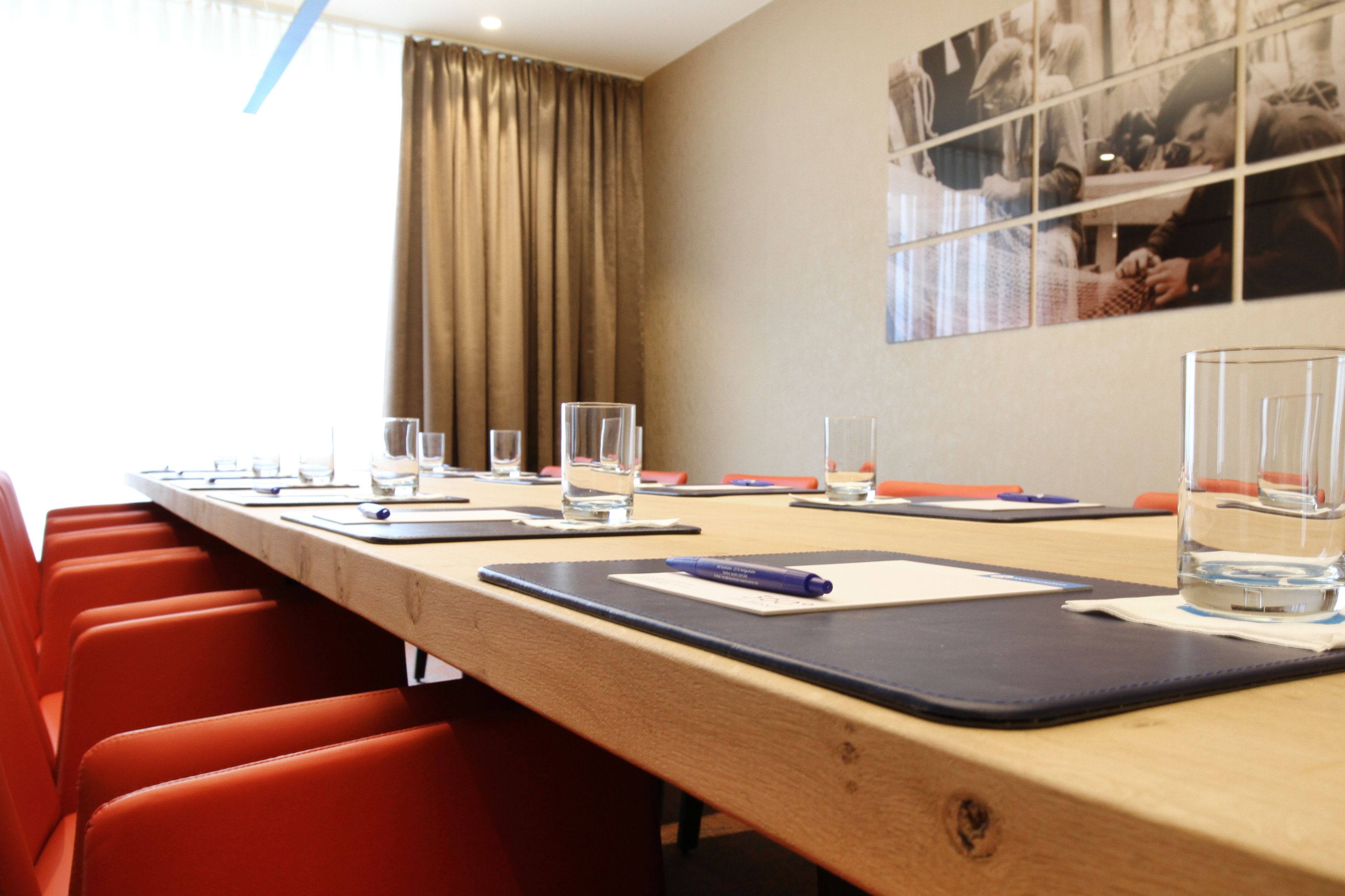 Una sala de conferencias con una mesa larga, sillas y botellas de agua de vidrio.