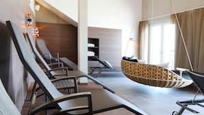 A modern spa room with reclining chairs, a hanging chair, and a massage table. - Hafenhotel Meereszeiten (Heiligenhafen)