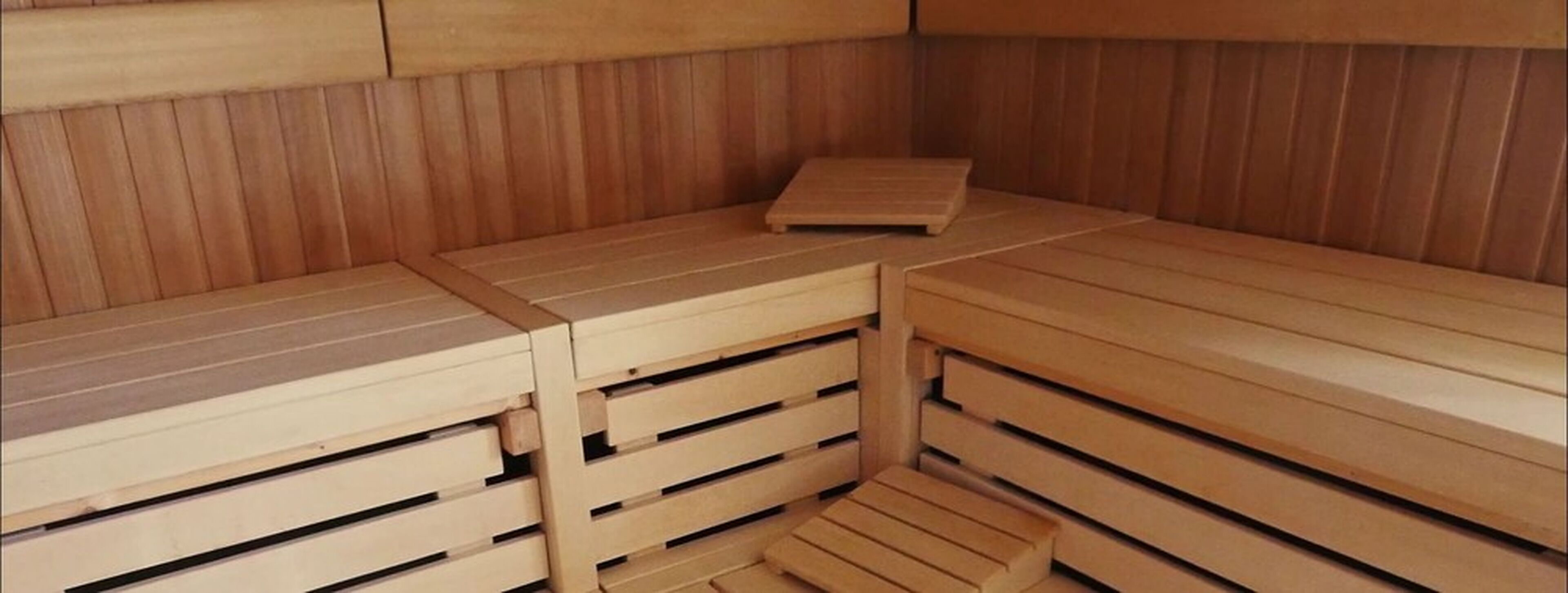 Una sauna con bancos de madera y un asiento.