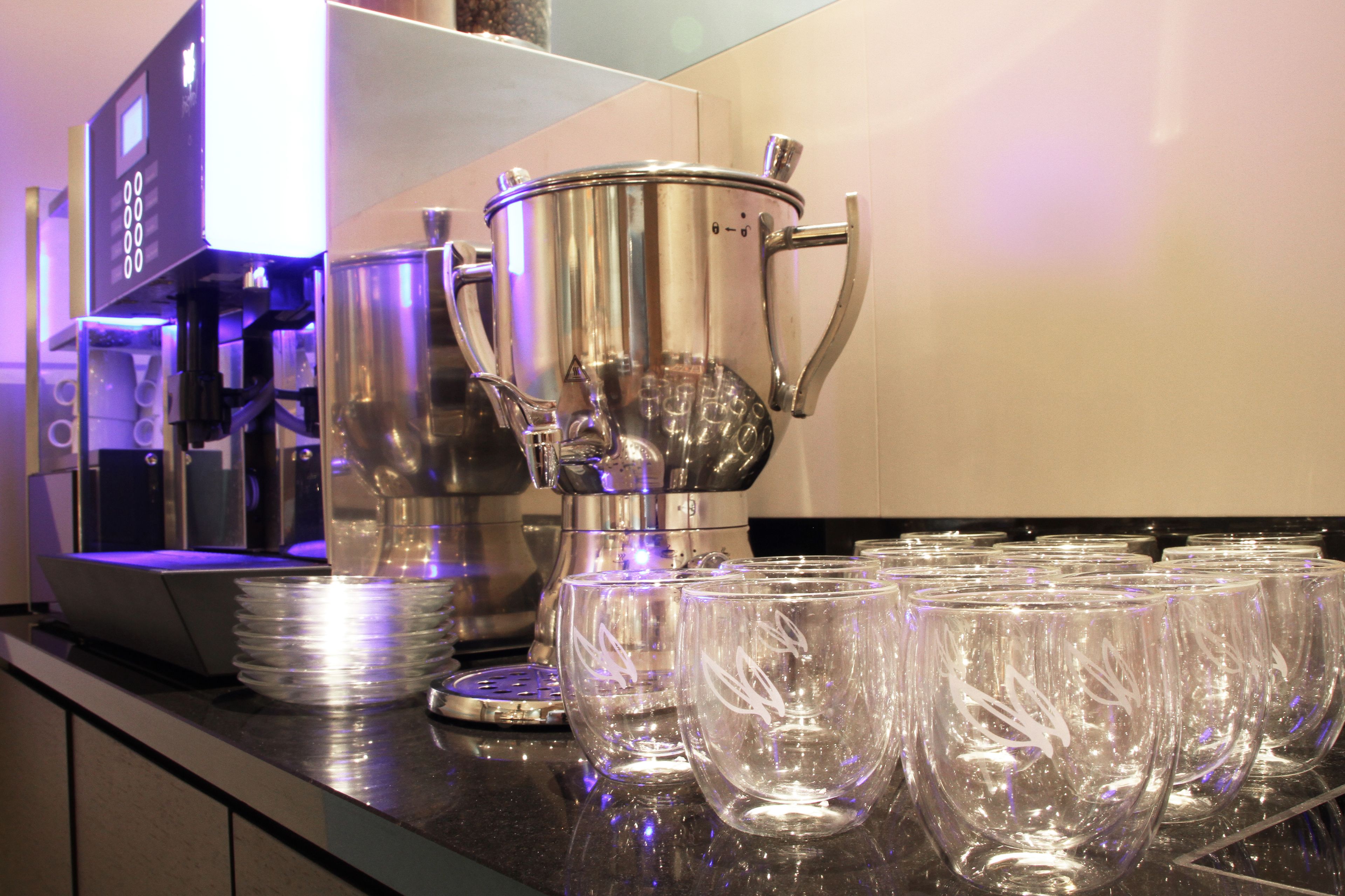 Un coin cuisine équipé d’une machine à café, d’une grande casserole et de plusieurs assiettes et verres empilés.