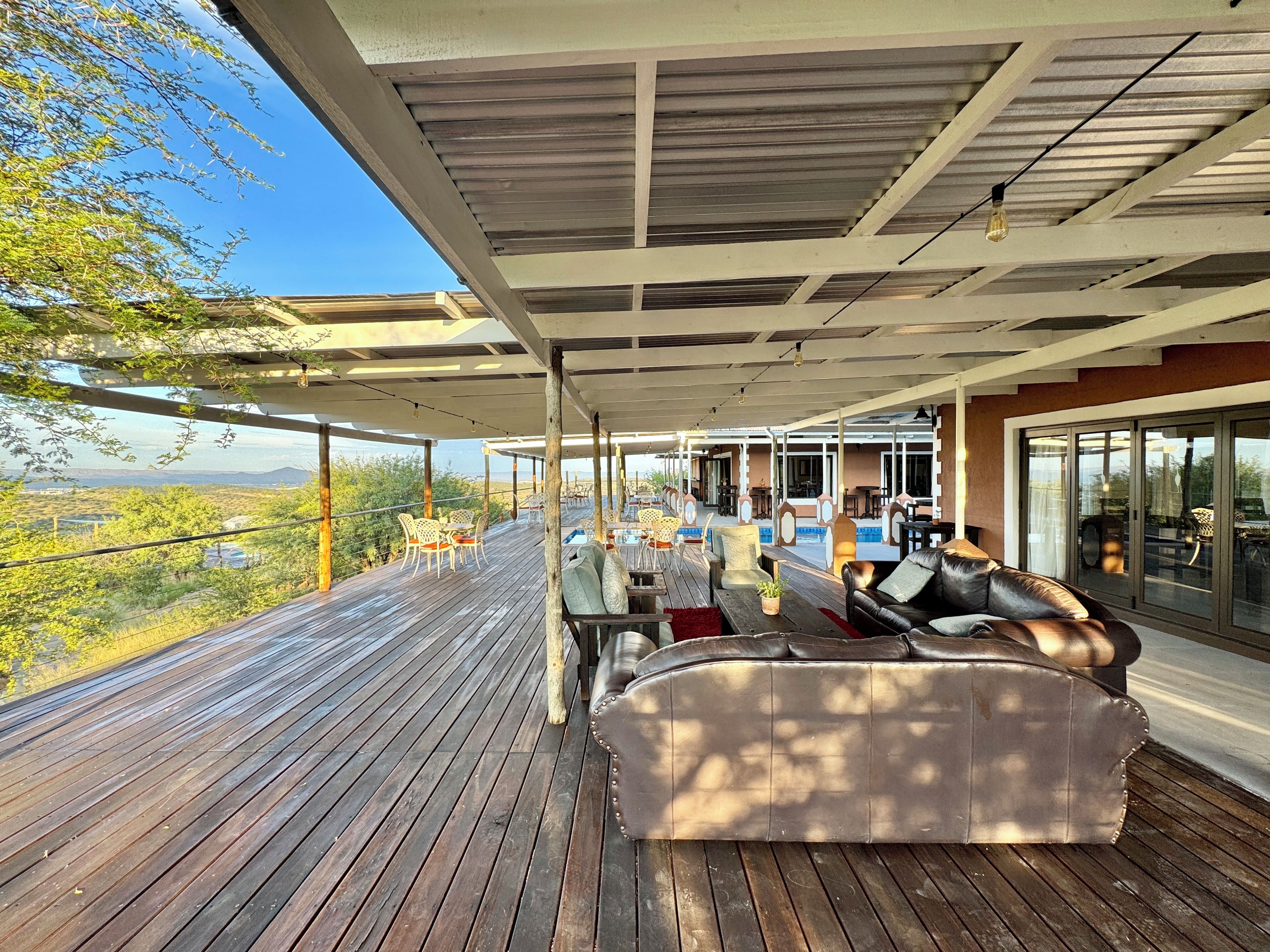 Ein überdachter Außenbereich mit Pool, Holzterrasse und Blick auf die Landschaft.