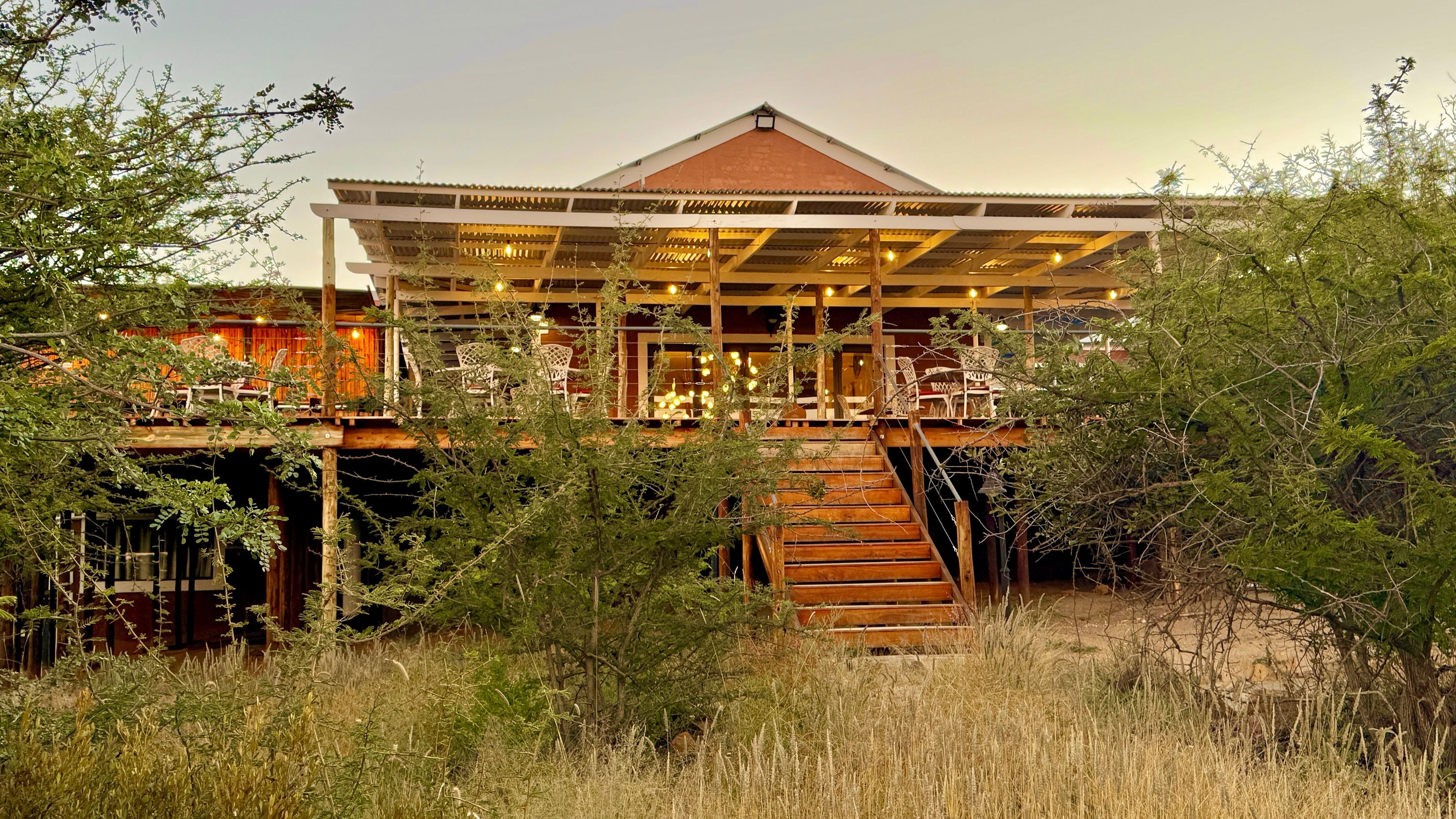A two-story building with a wooden deck and a staircase leading to the upper level.