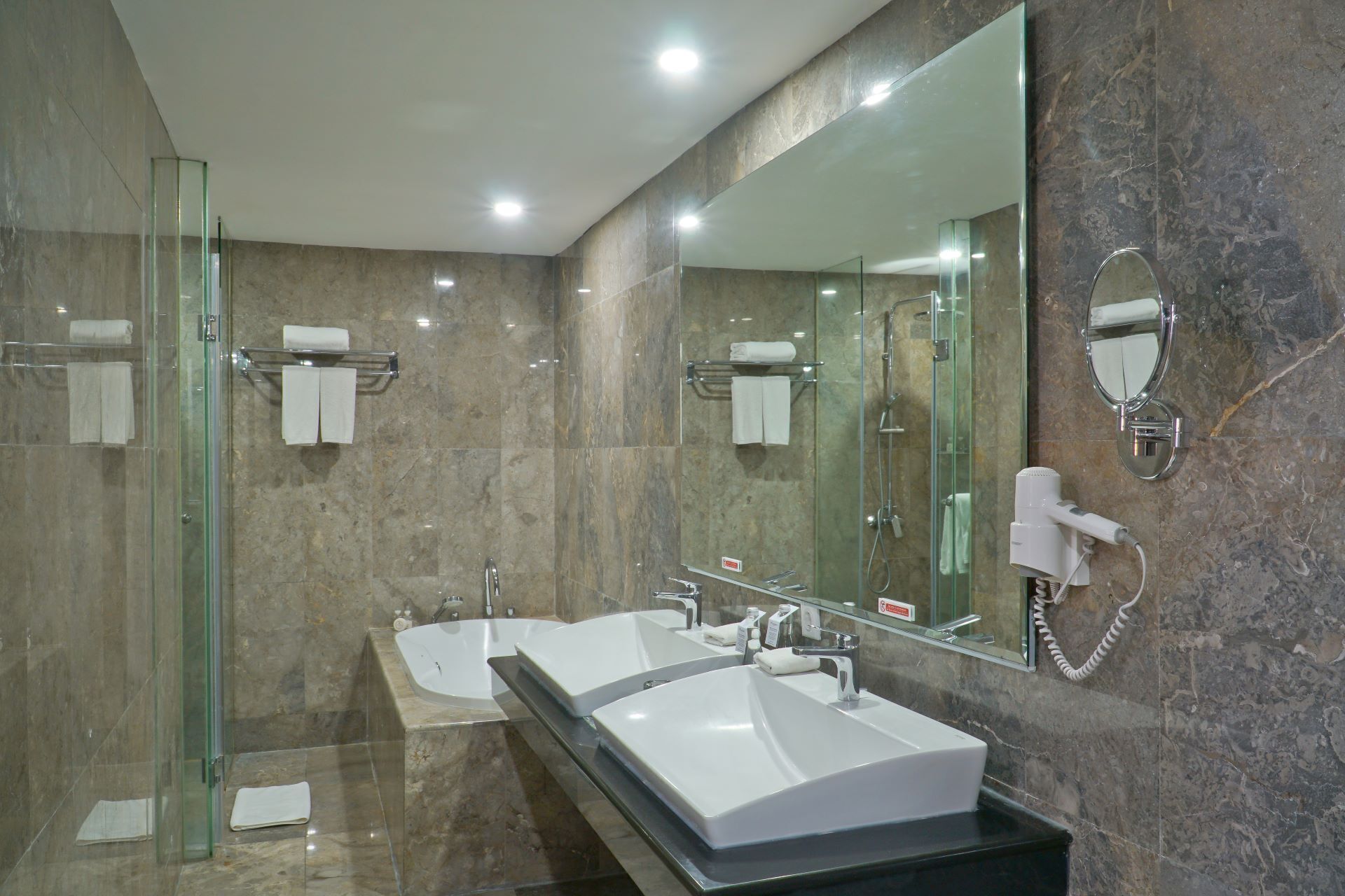 A modern bathroom with a glass shower enclosure, a double sink vanity, and a large mirror.