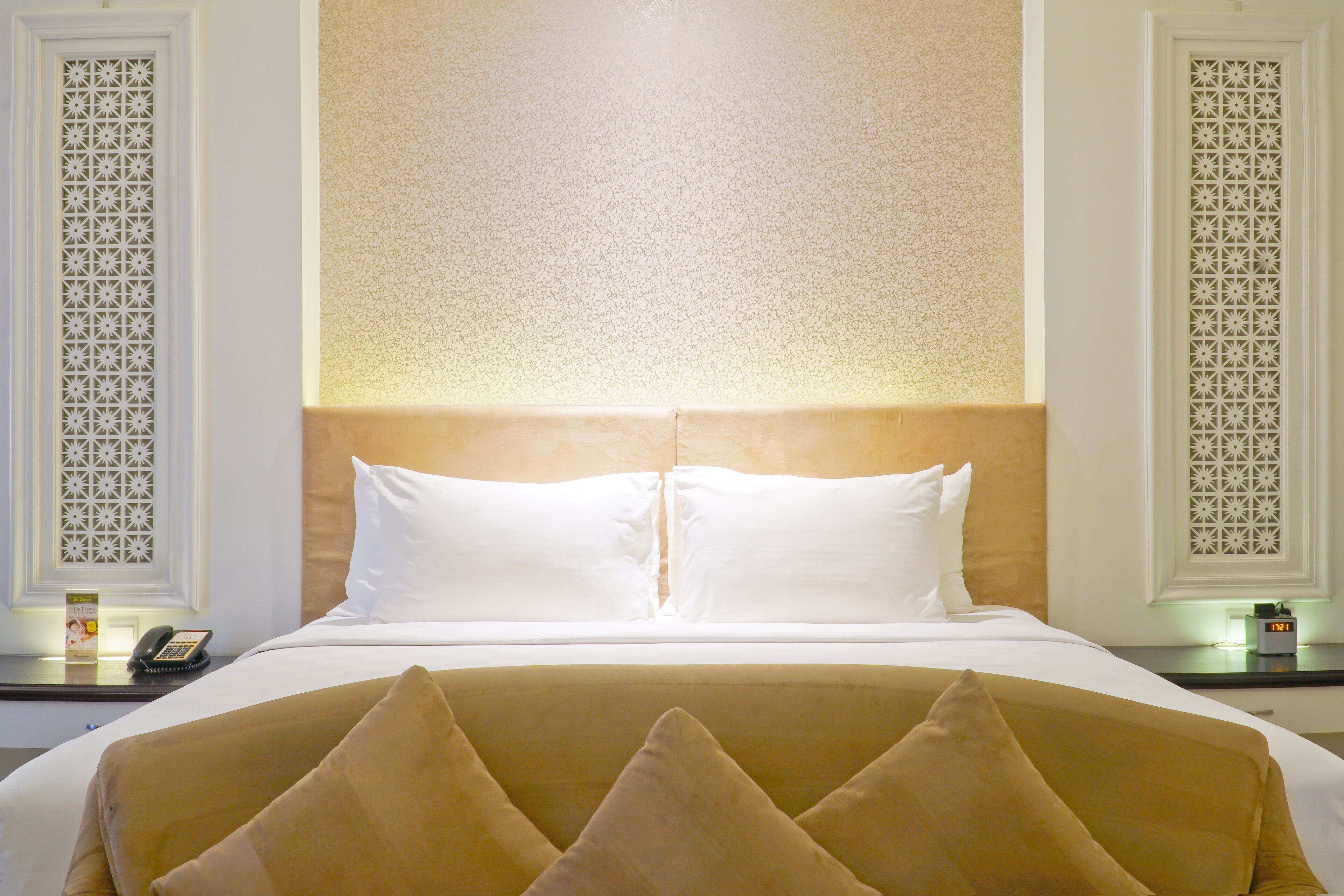 A hotel room with a large bed, two bedside tables, and a decorative wall panel.