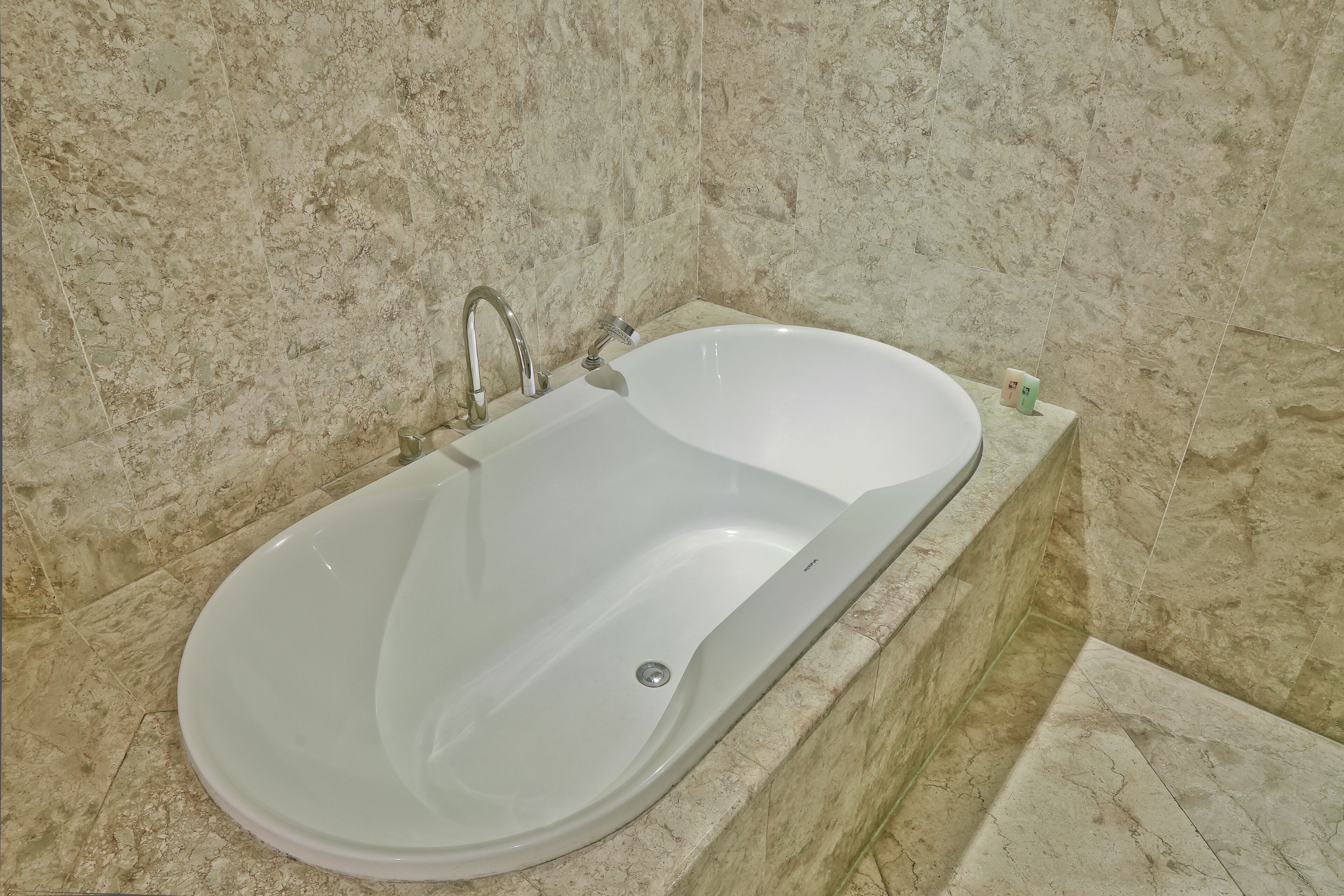 A modern bathroom with a freestanding bathtub, marble walls, and a marble floor.