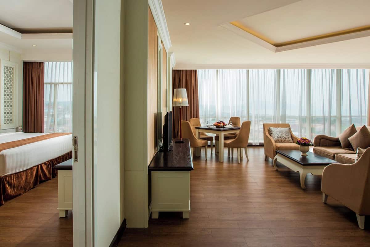 Une chambre d’hôtel comprenant un lit, un bureau avec une lampe, une table à manger avec des chaises et un canapé.