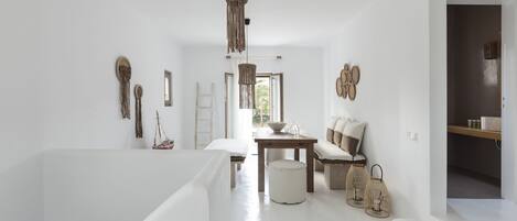 A spacious room with a high ceiling, a wooden dining table, a sofa, and a hanging light fixture.