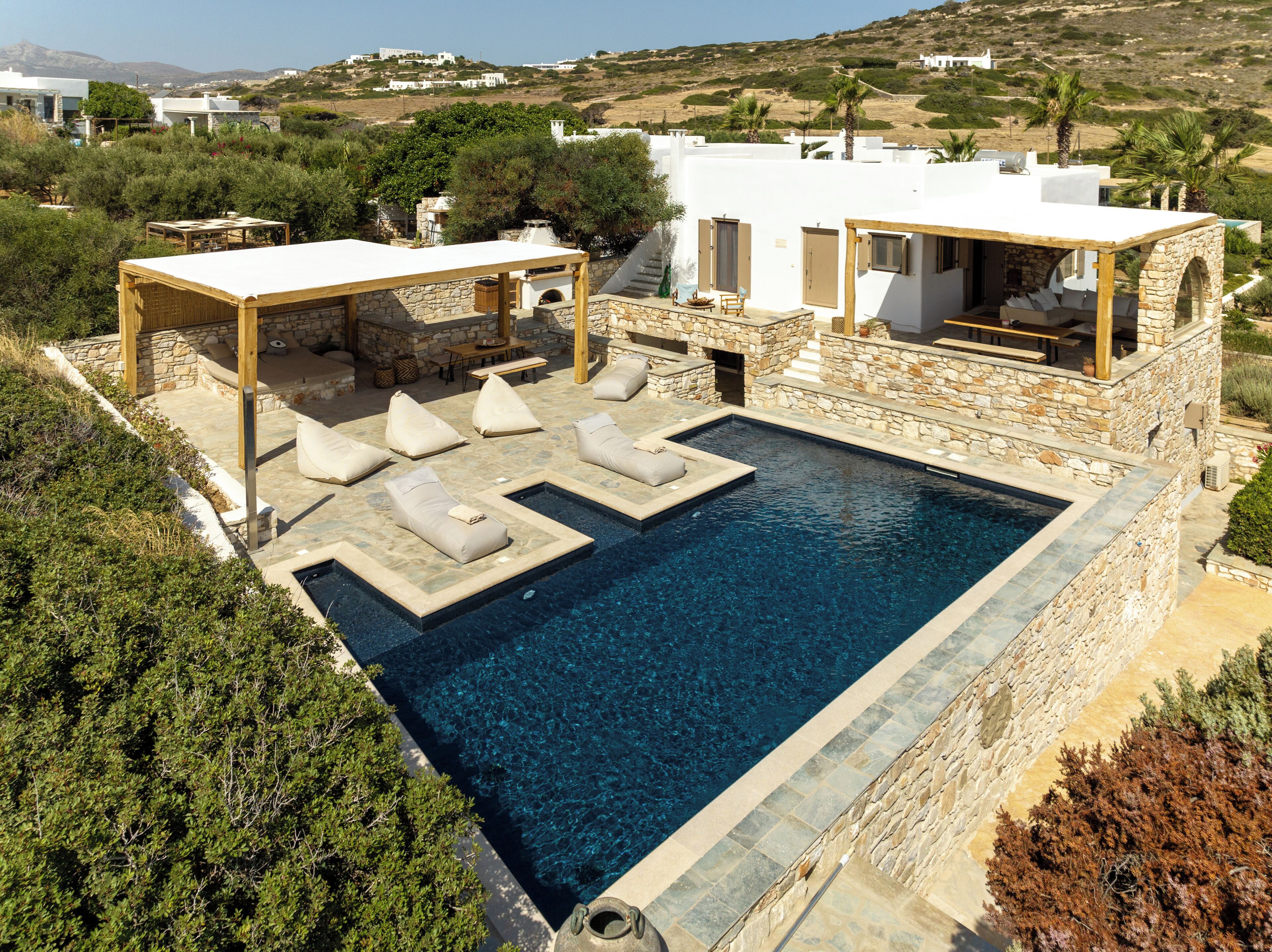 A modern villa with a swimming pool, outdoor seating, and a stone exterior.