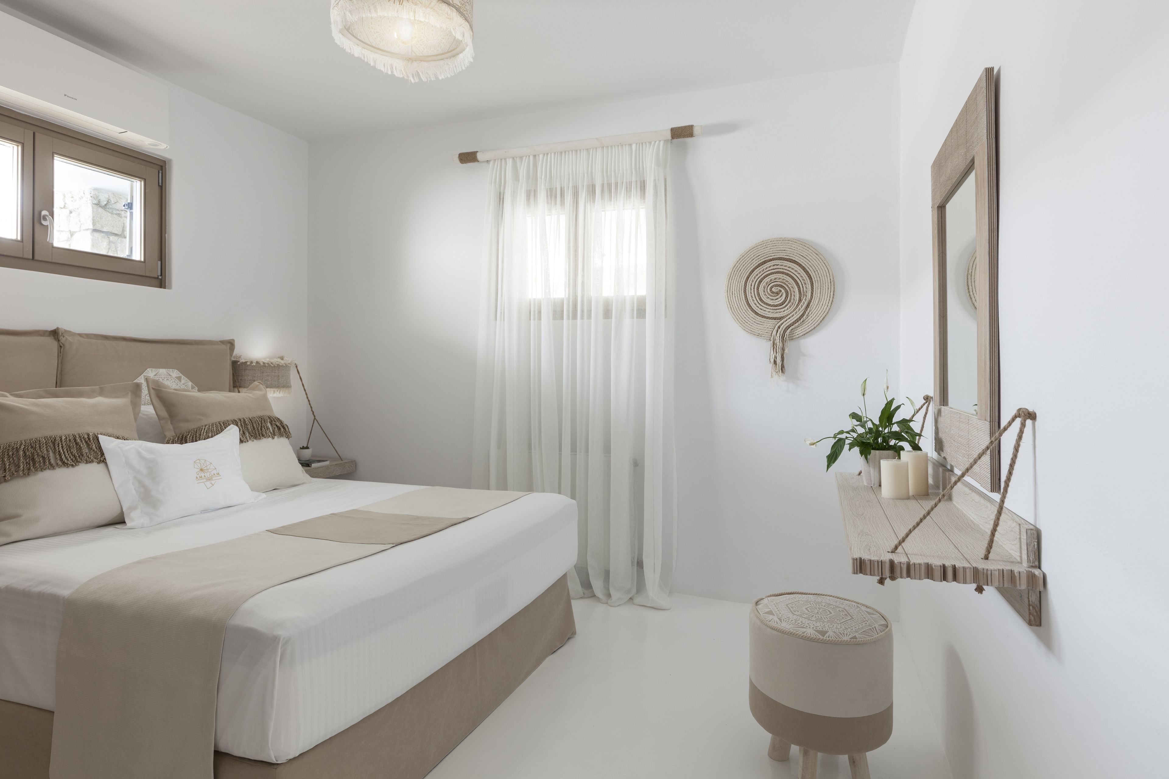 Un dormitorio moderno con una cama grande, una mesita de noche con una planta, un espejo colgado y una ventana con cortinas.