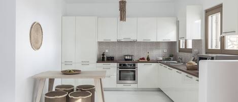 Una cocina moderna con armarios blancos, una mesa de madera y una lámpara colgante.