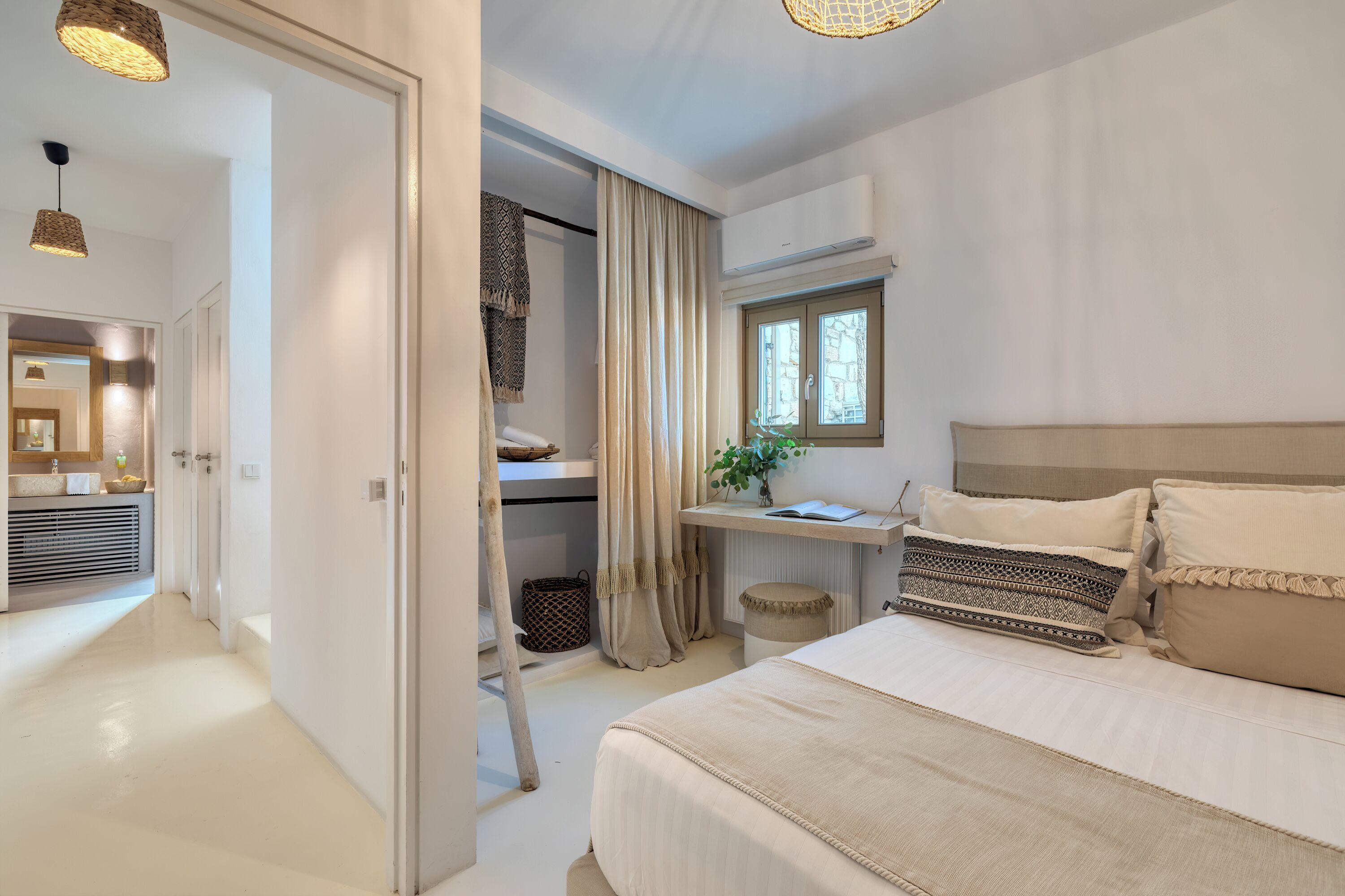 Quarto com cama, mesa de cabeceira, cortinas e janela.