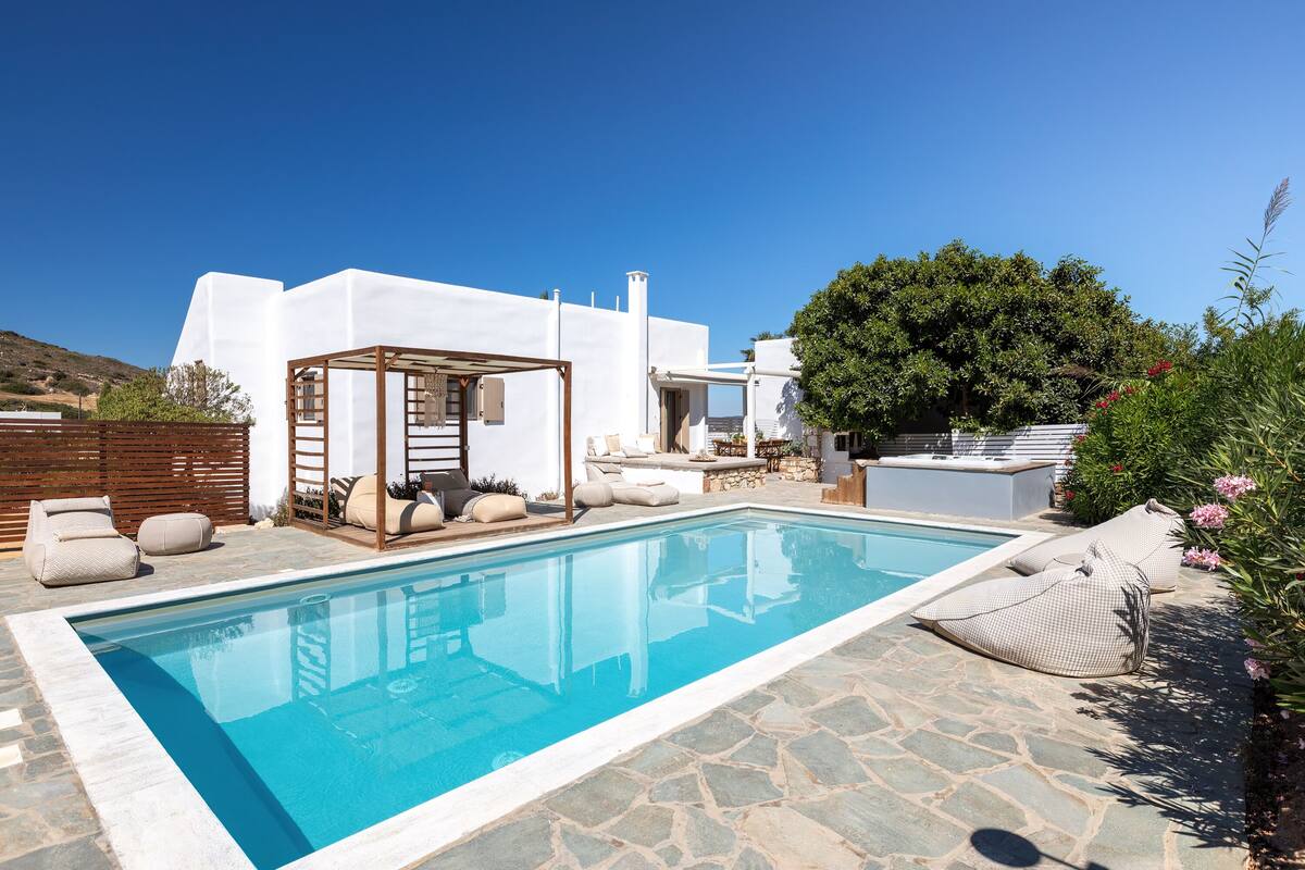 A modern pool area with a clear blue pool, stone flooring, and outdoor seating.