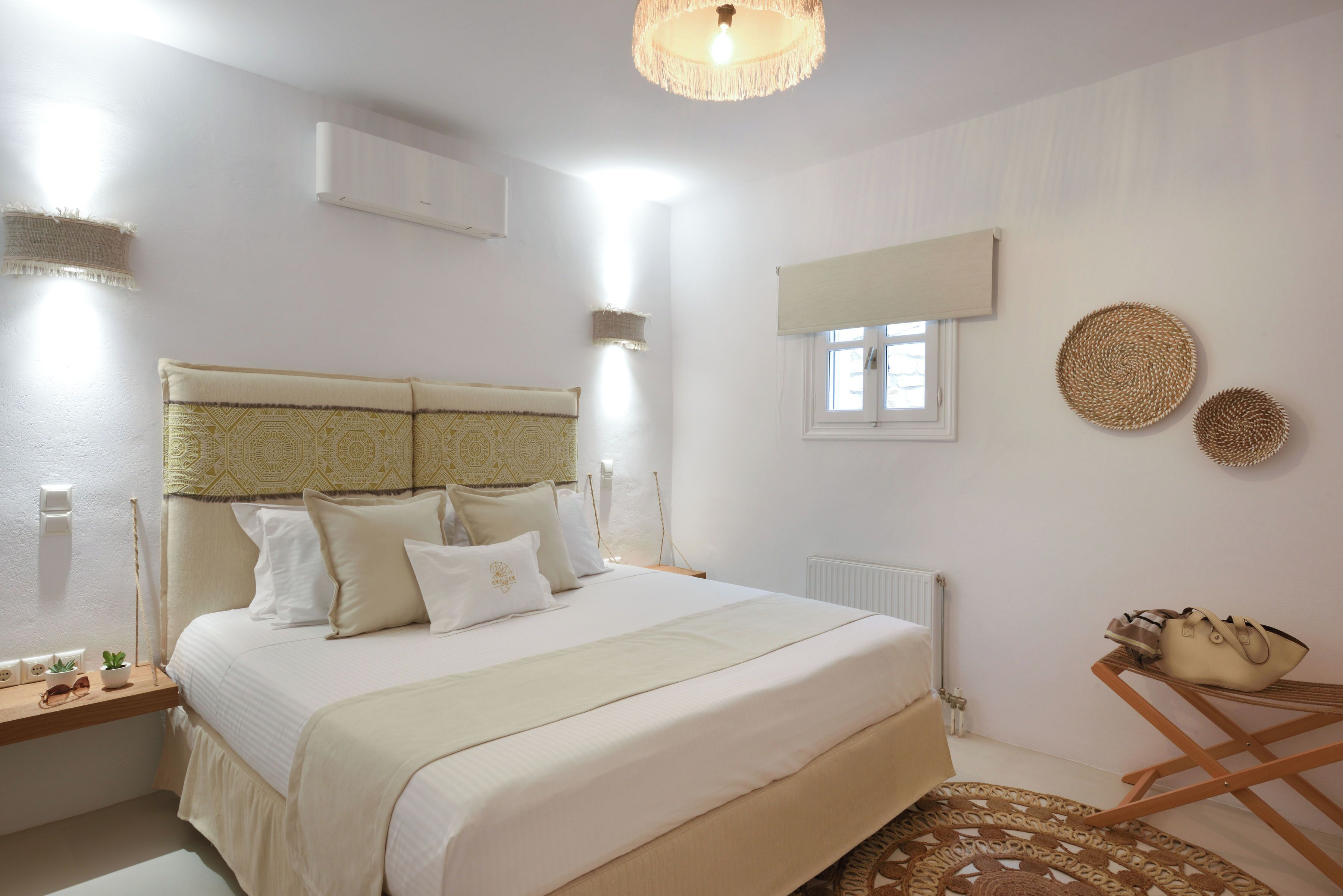 Une chambre à coucher avec un grand lit, des tables de chevet, une fenêtre et un luminaire au plafond.