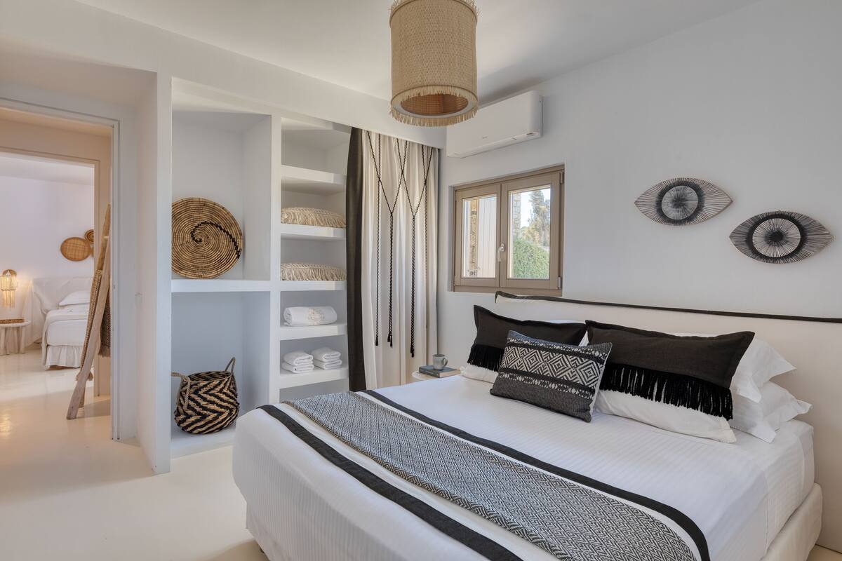 A modern bedroom with a large bed, a wardrobe, and a hanging light fixture.