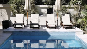 Relax by the serene pool surrounded by lounge chairs and lush greenery.