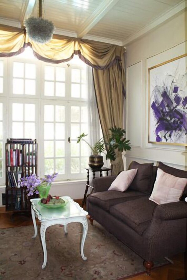 Una sala acogedora con un sofá marrón, una mesa de centro de cristal con un jarrón verde y una estantería.