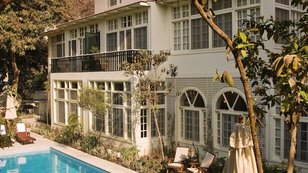 A two-story building with a swimming pool, surrounded by lush greenery and a large tree. - Villa Belle Epoque (Cairo)