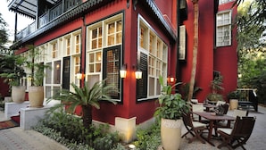 A red building with large windows, outdoor seating, and potted plants. - Villa Belle Epoque (Cairo)