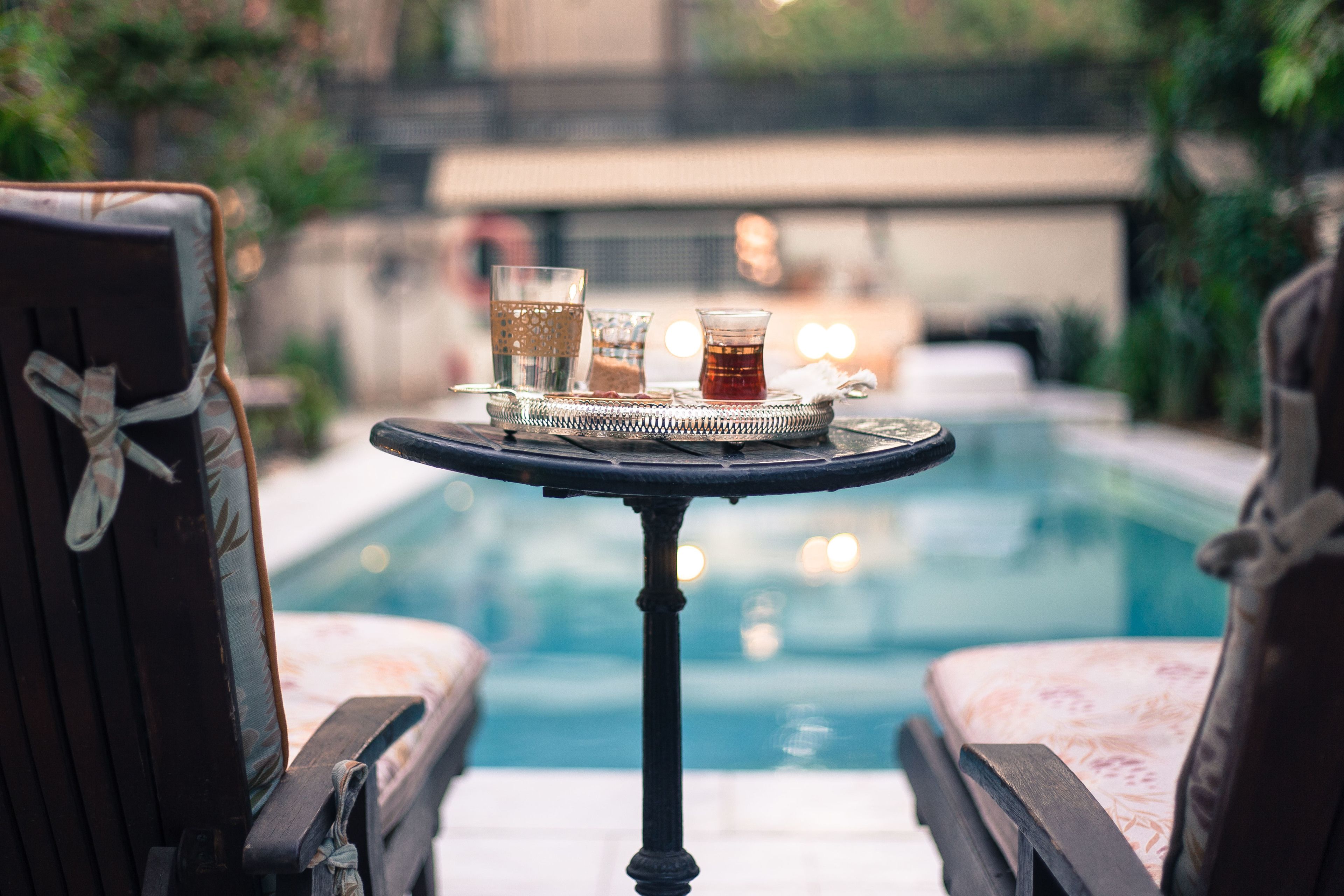Un espace aménagé au bord de la piscine, avec une table sur laquelle sont posés des verres et une bouteille, entourée de chaises longues.