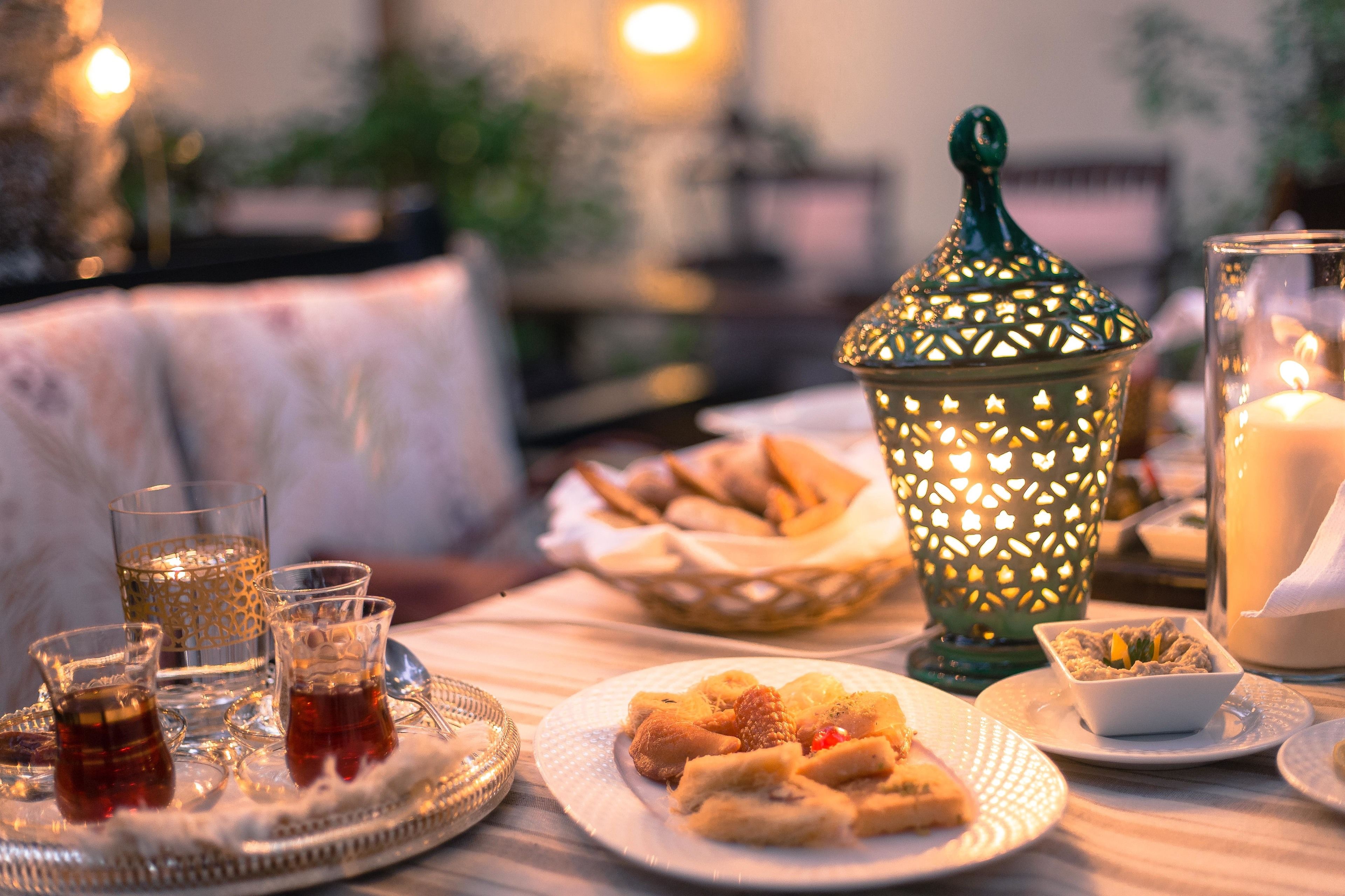 A table set with glasses of tea, pastries, and a decorative lantern.