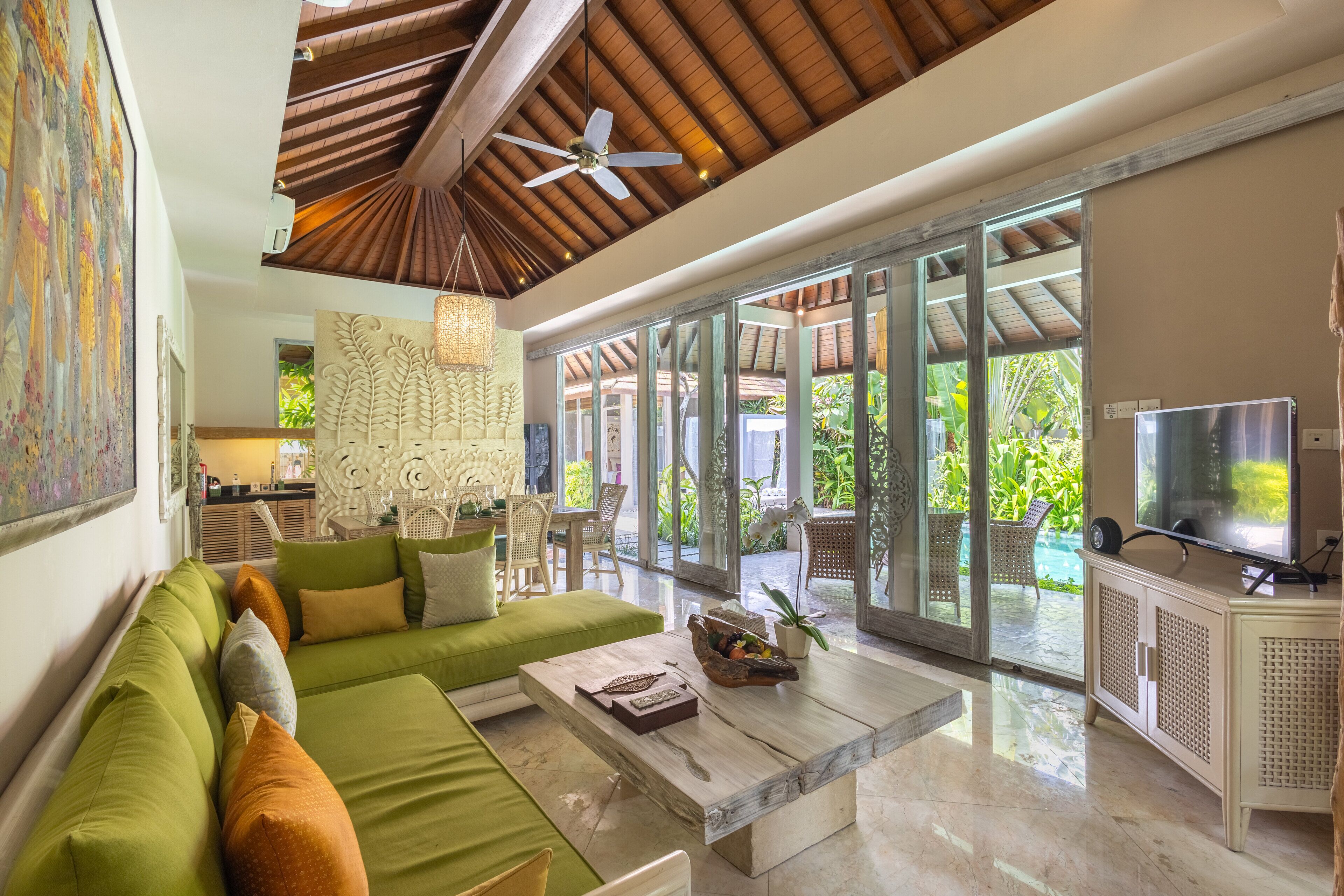 A spacious living area with a green sofa, a coffee table, and a television.