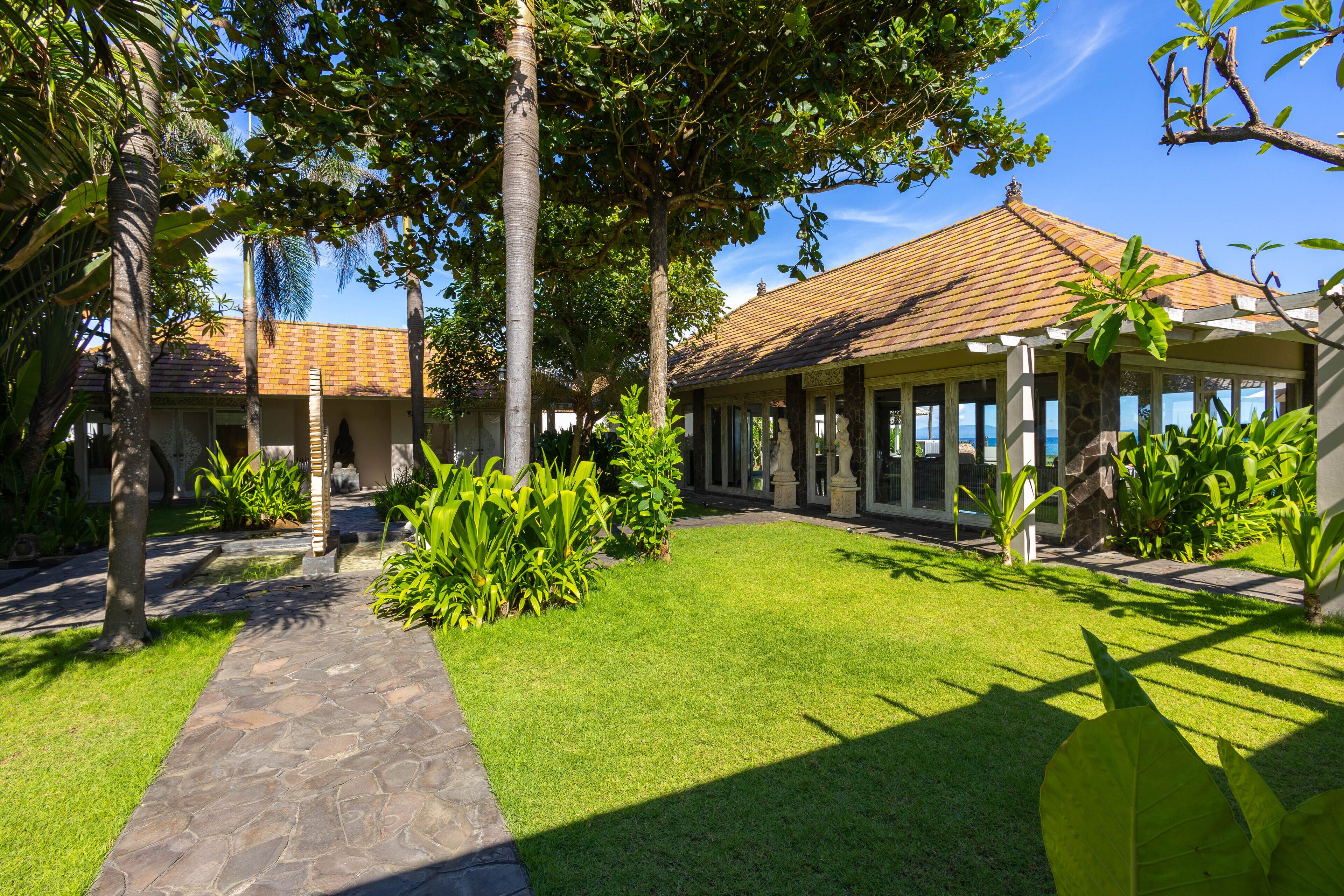 A courtyard with a stone pathway, lush green lawn, and a building with a tiled roof.