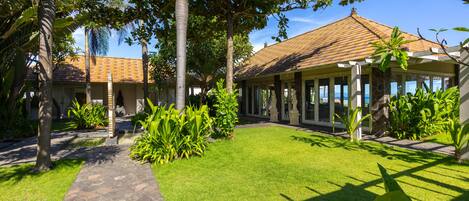 A courtyard with a stone pathway, lush green lawn, and a building with a tiled roof.